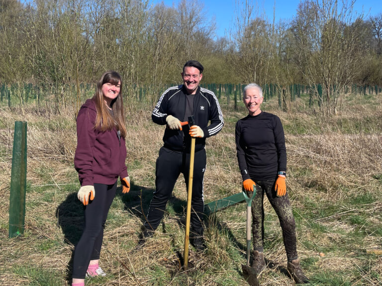 three volunteers from a business taking part in tree maintenance in stockport