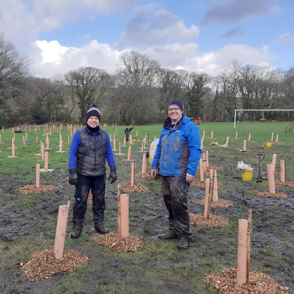 Two men smiling among planted trees