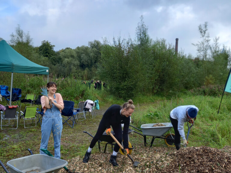 3 individuals shovelling woodchip