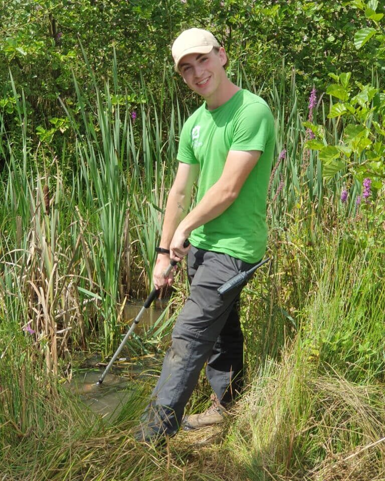 Male team member smiling in grassy woodland