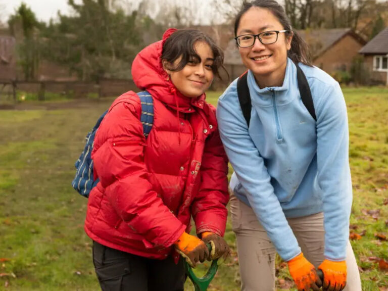 A woman and young girl working together outdoors