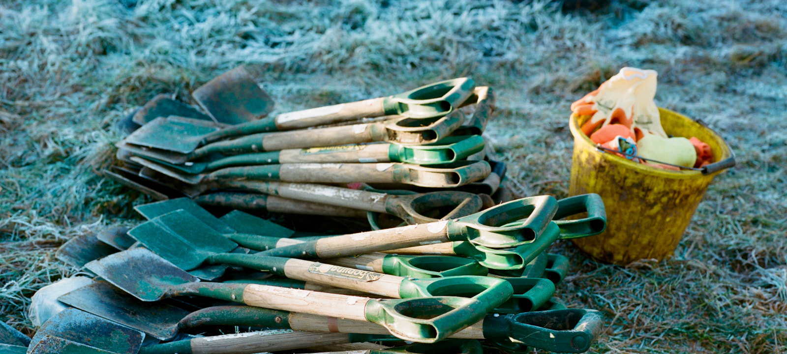 spades in the frosty grass with a bucket