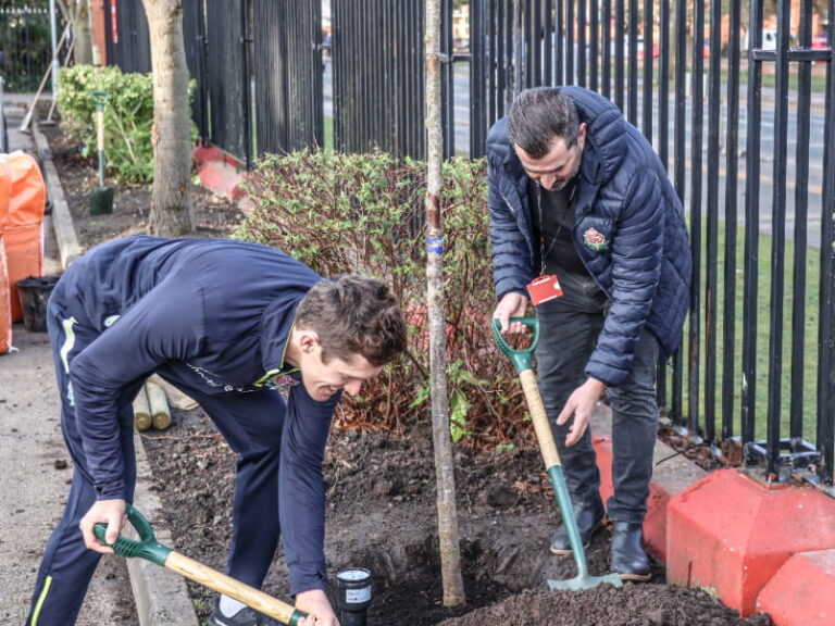 Two members of cricket club planting standards in grounds