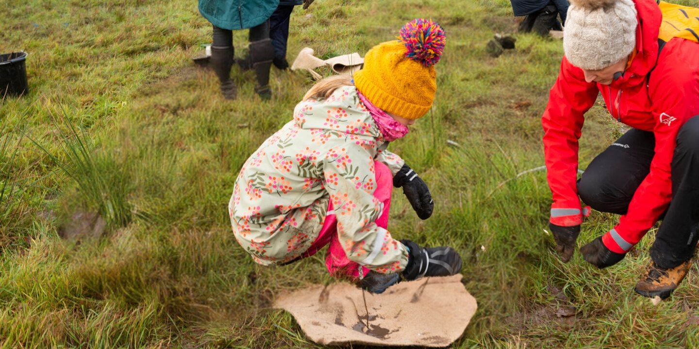 Mother showing daughter how to plant tree