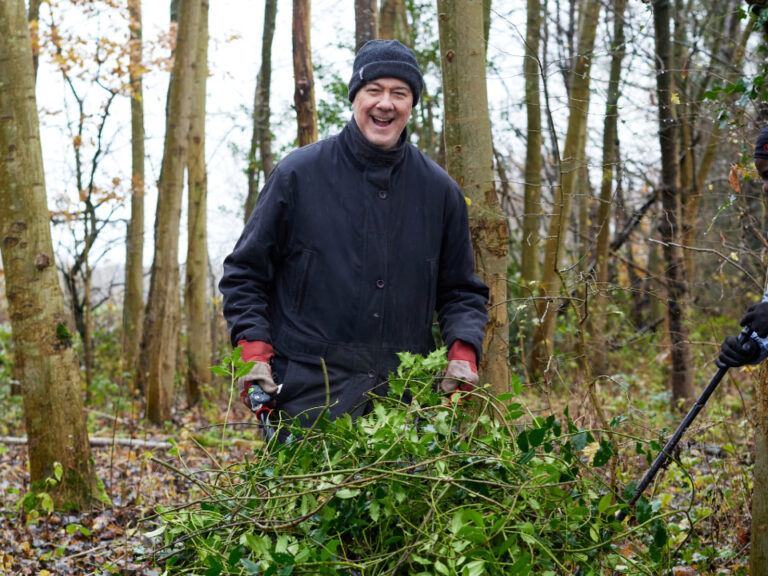 two men taking part in woodland management with a wheel barrow