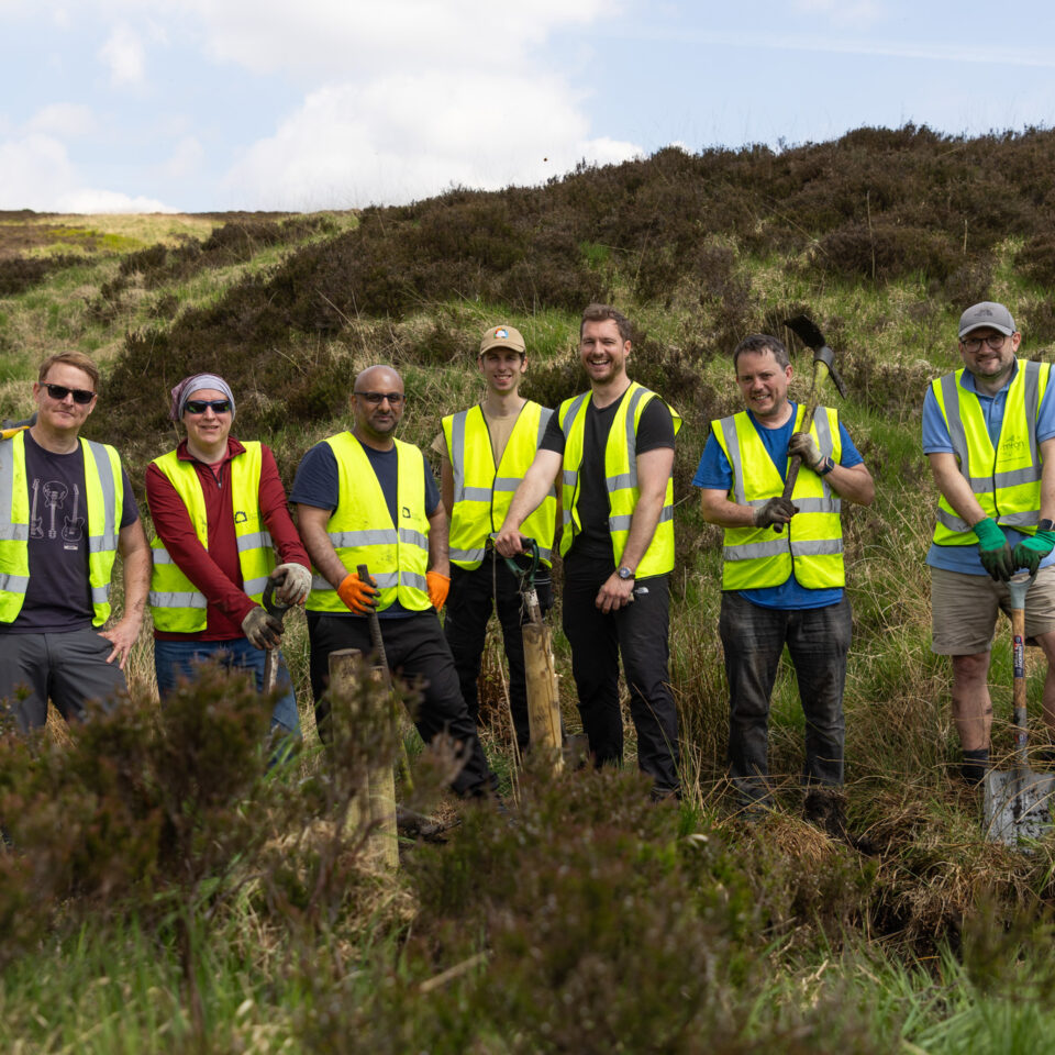 five volunteers from BUPA smiling in yellow high vis at site
